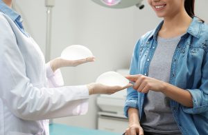 Doctor showing silicone implants for breast augmentation to patient in clinic