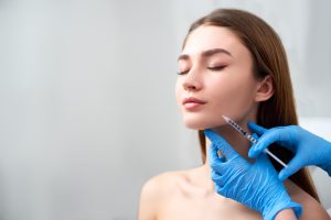 Woman recieving a syringe of fillers into her cheek.